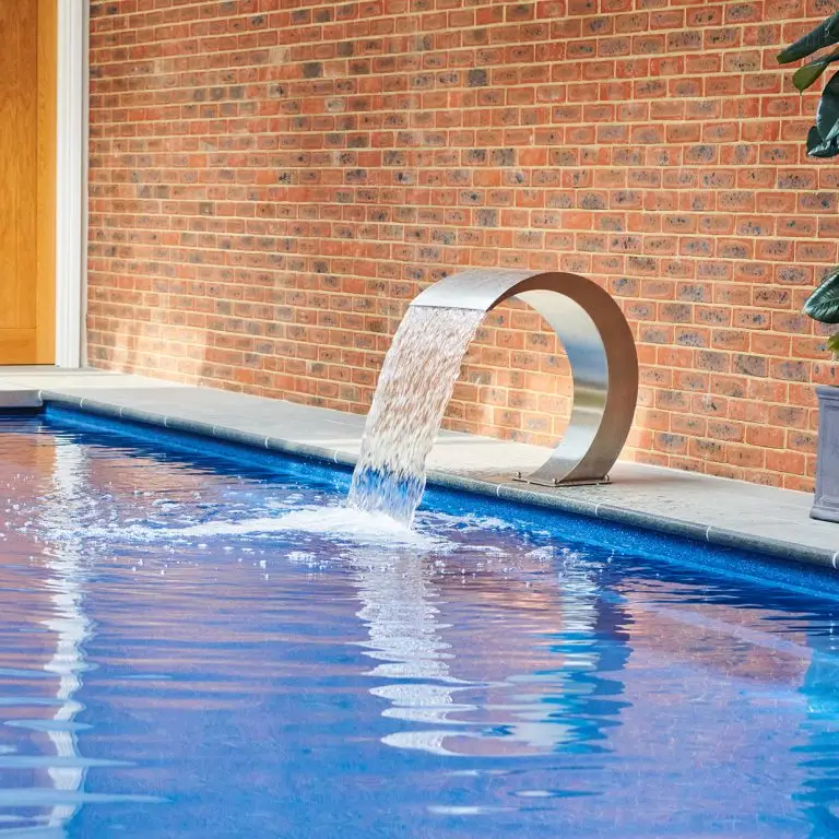 A luxury indoor swimming pool with a curved waterfall feature, creating a smooth cascade of water for a spa-like experience.